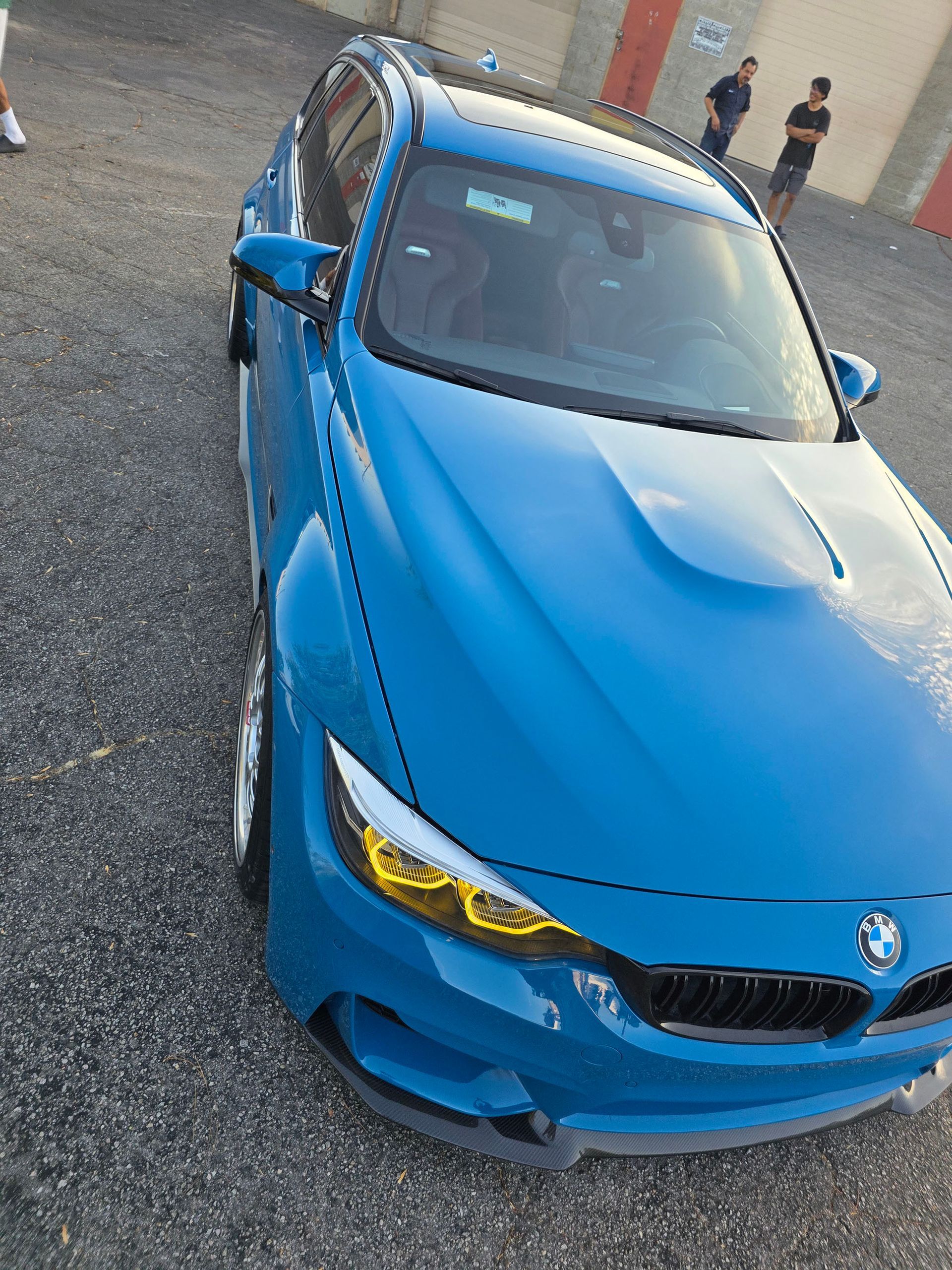 Blue BMW sedan parked on a gravel lot, front-left view