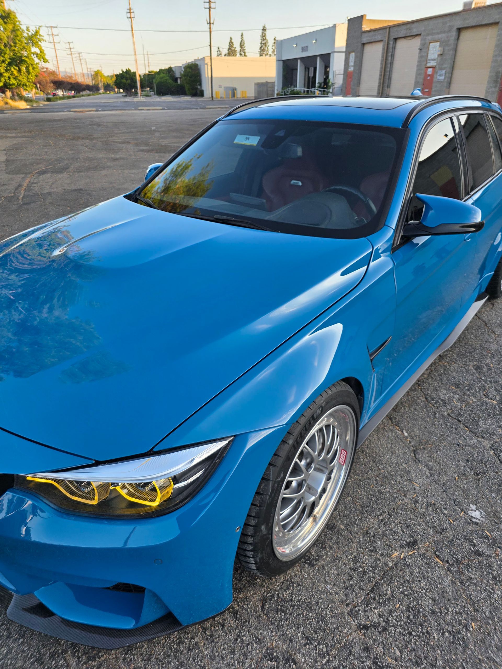 Blue BMW sedan parked on a street in daylight, front-left view