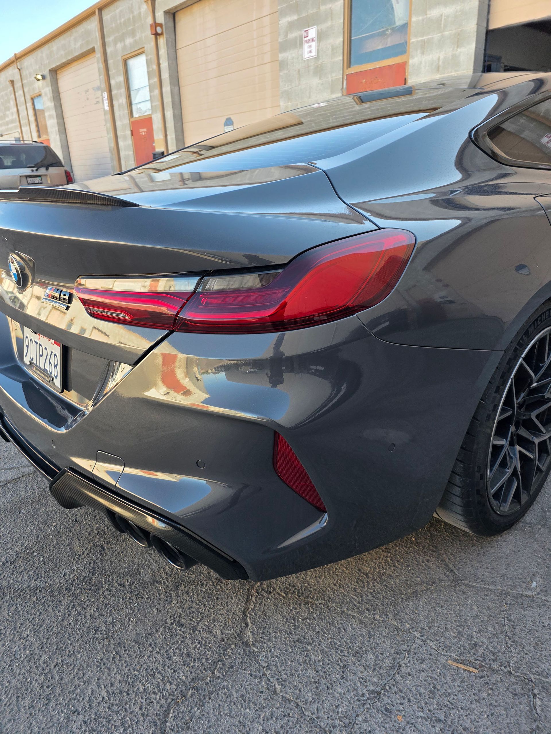 Rear view of a gray sports sedan parked beside a brick building