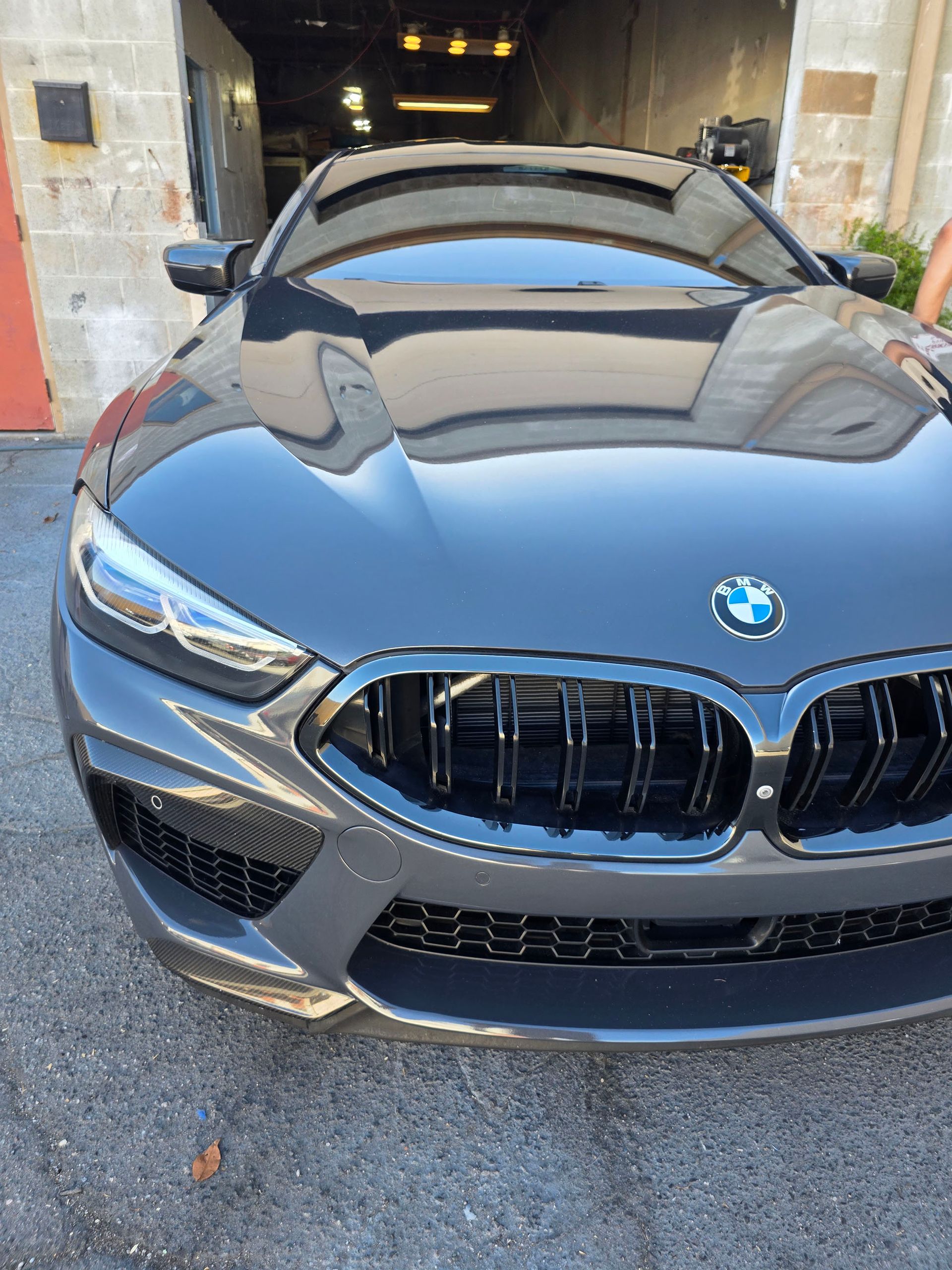 Gray BMW convertible parked in a garage, front view with top down.