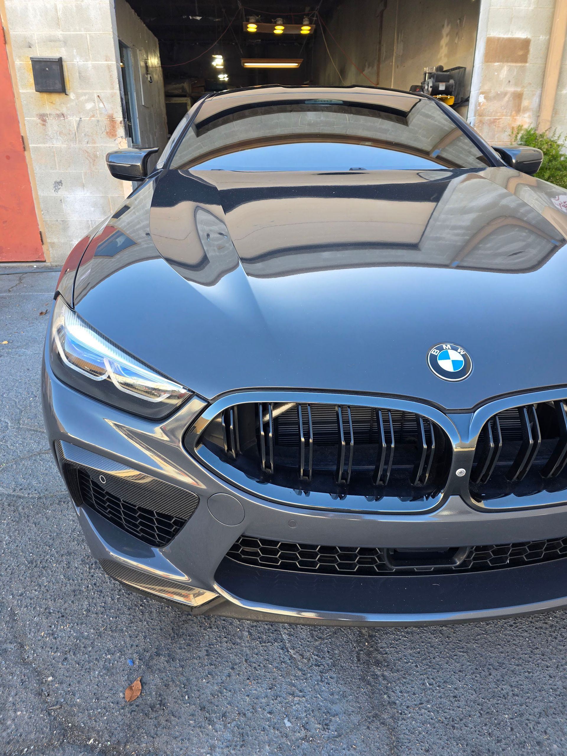 Front view of a gray BMW sports coupe parked in a garage entrance