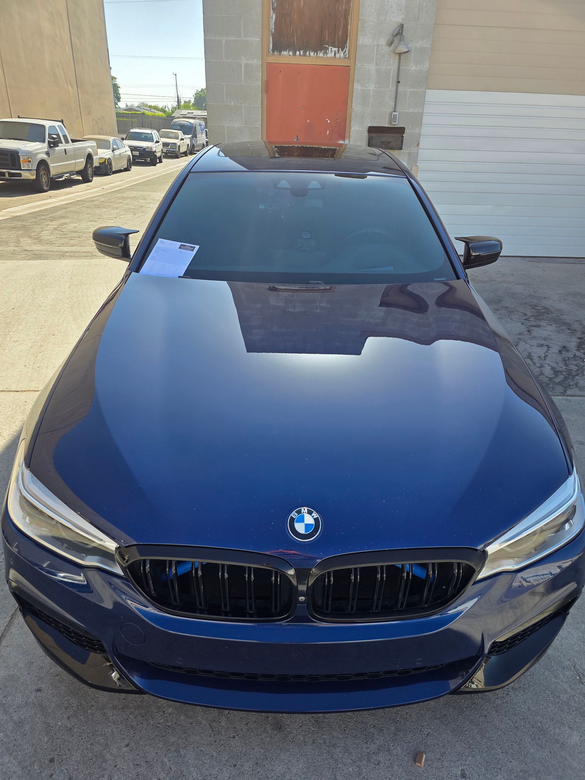 Blue BMW sedan parked in a narrow alley beside brick buildings, front view.
