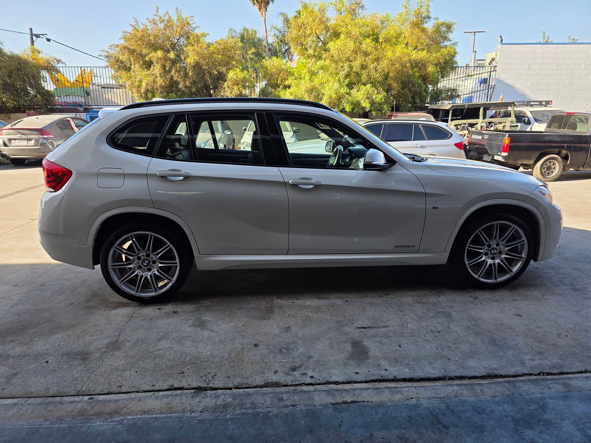 Silver SUV parked outdoors on a concrete lot with trees and other vehicles in the background