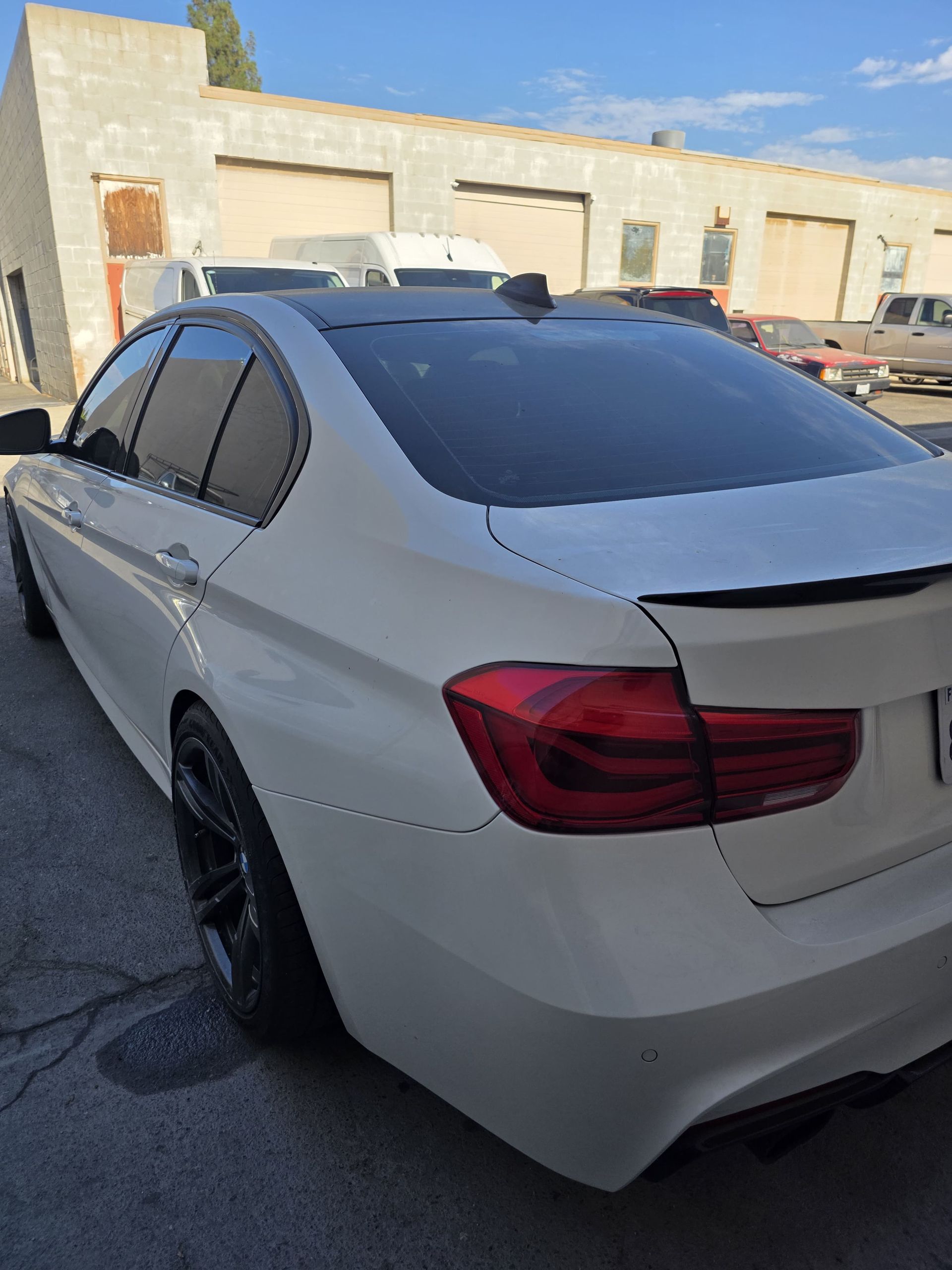 White sedan with tinted windows parked outside a garage in bright daylight