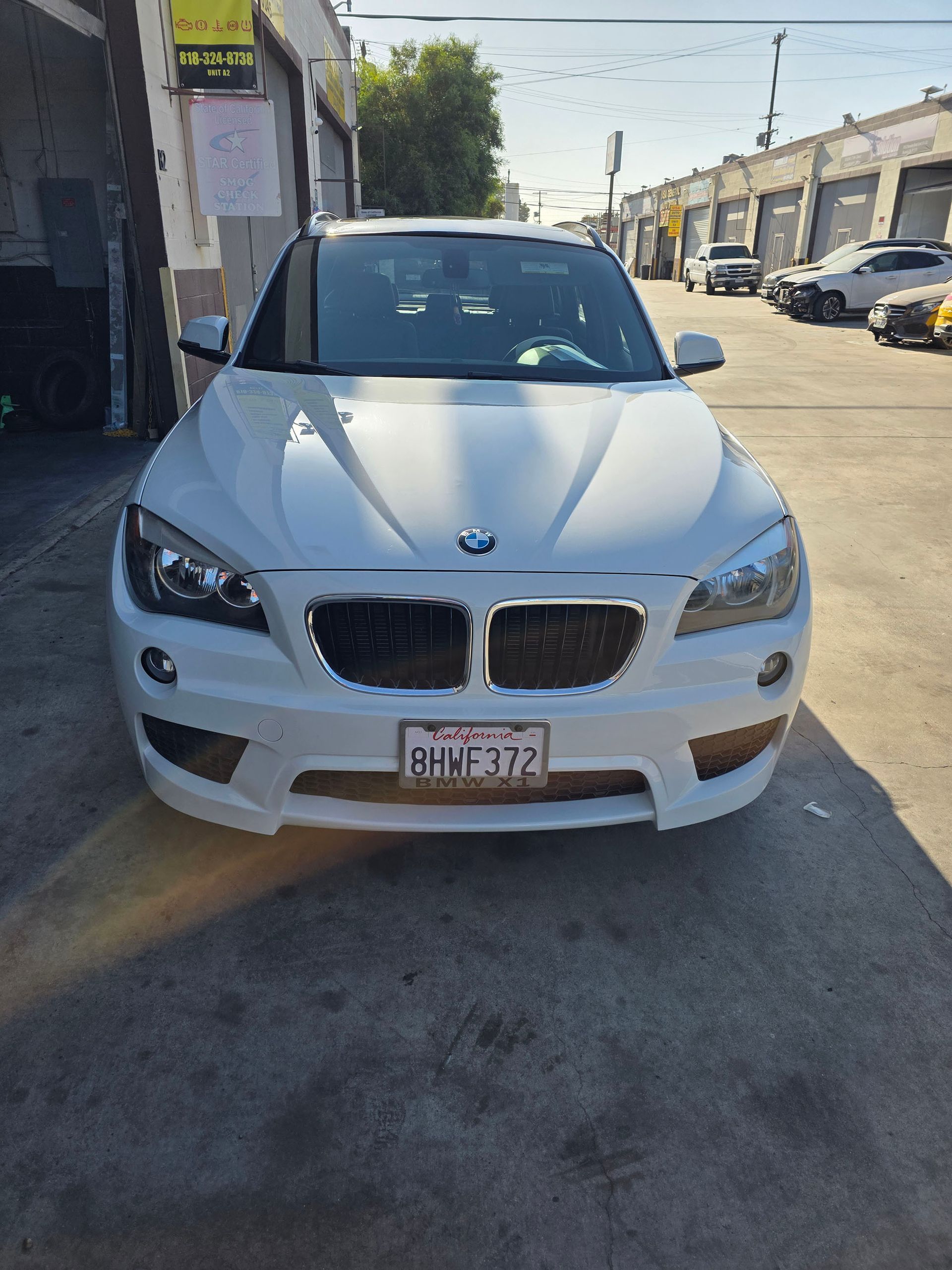 White BMW SUV parked on a sunny street outside industrial buildings
