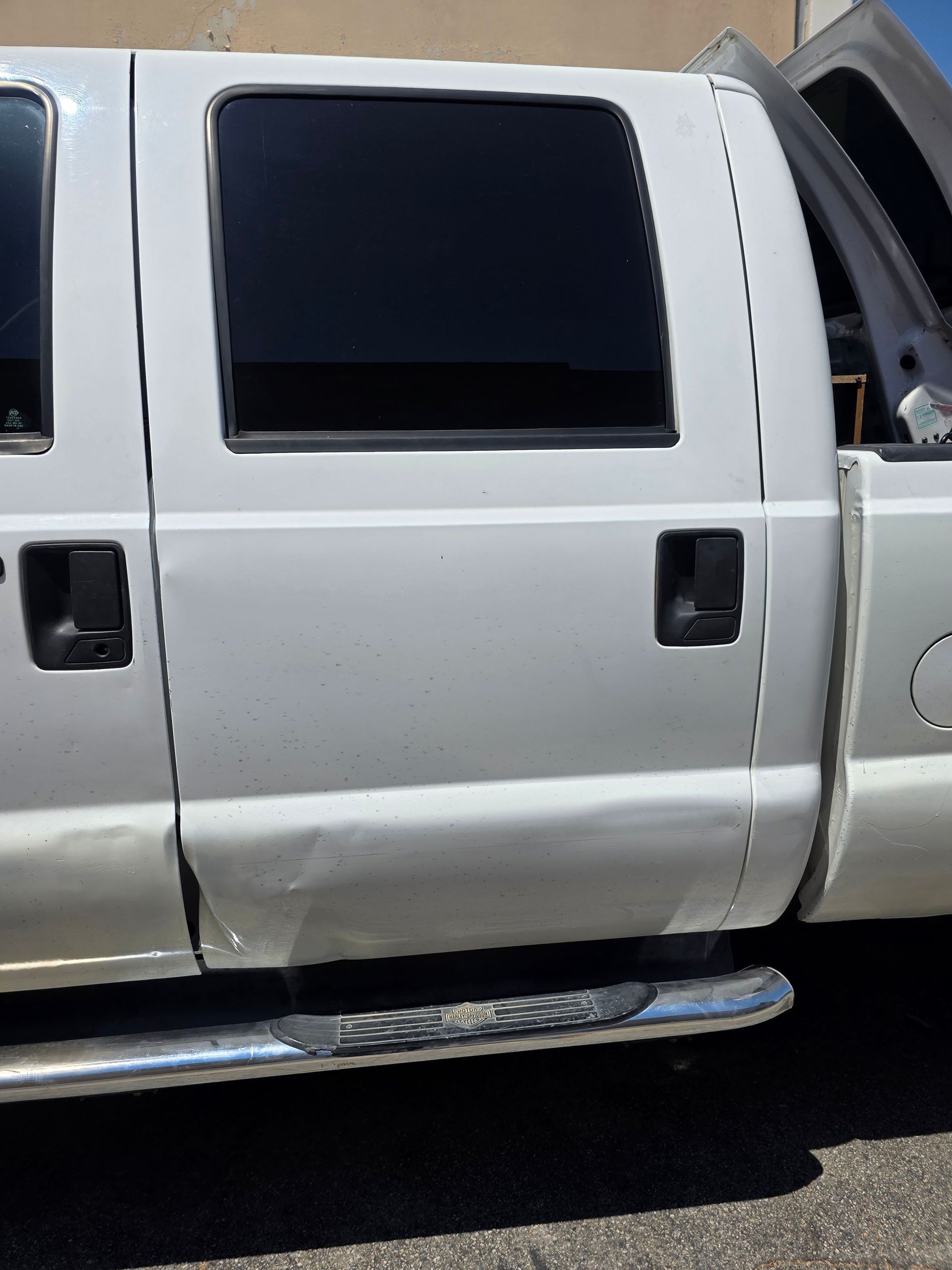 White pickup truck with dark tinted windows and a chrome side step, parked outdoors.