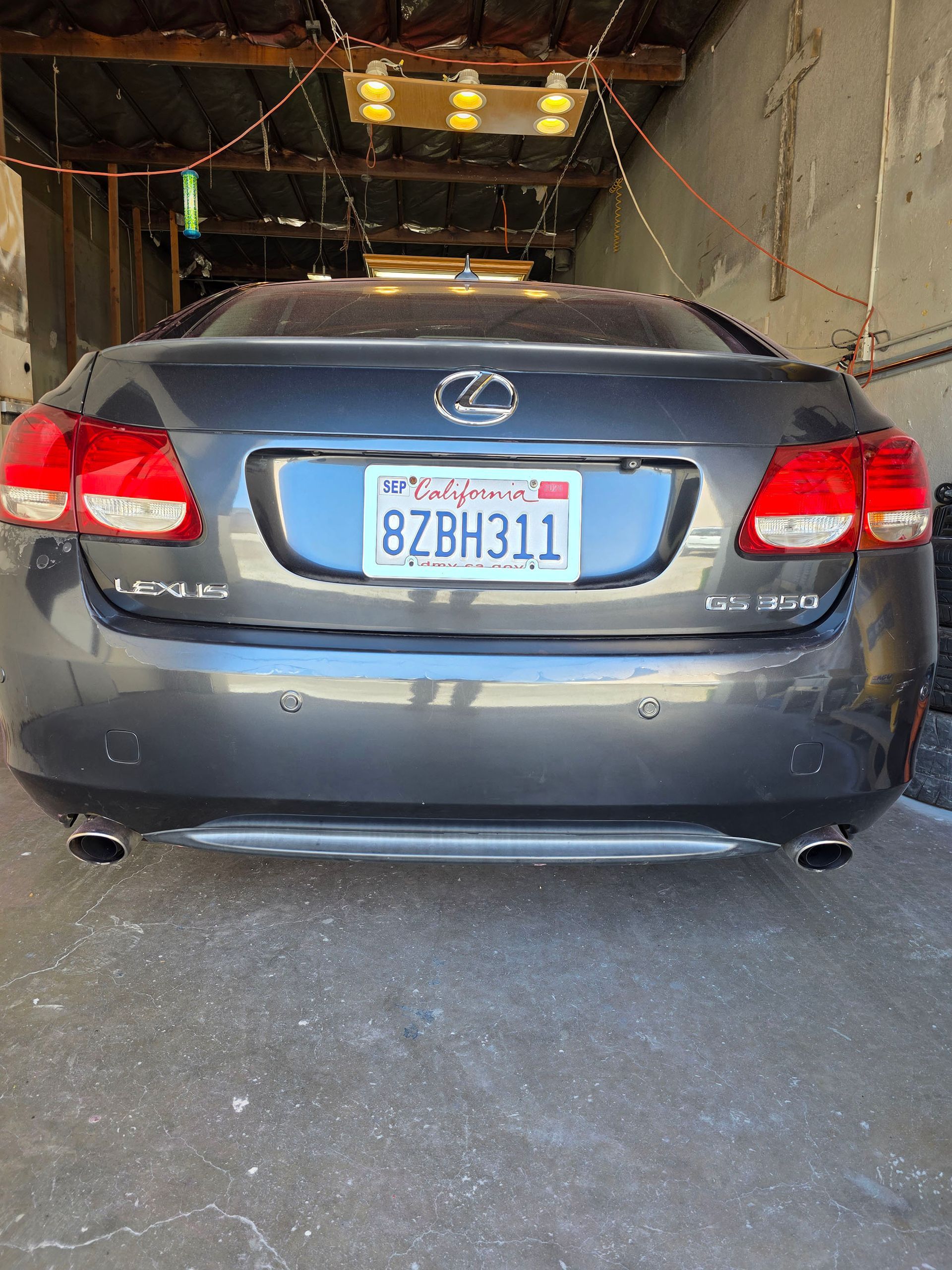 Gray Lexus sedan parked in a garage, viewed from the rear, with a California license plate.
