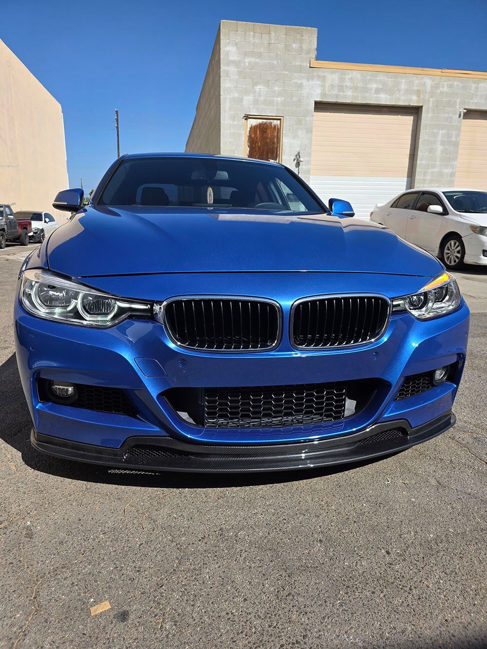 Blue BMW sedan parked outdoors in front of a building on a sunny day
