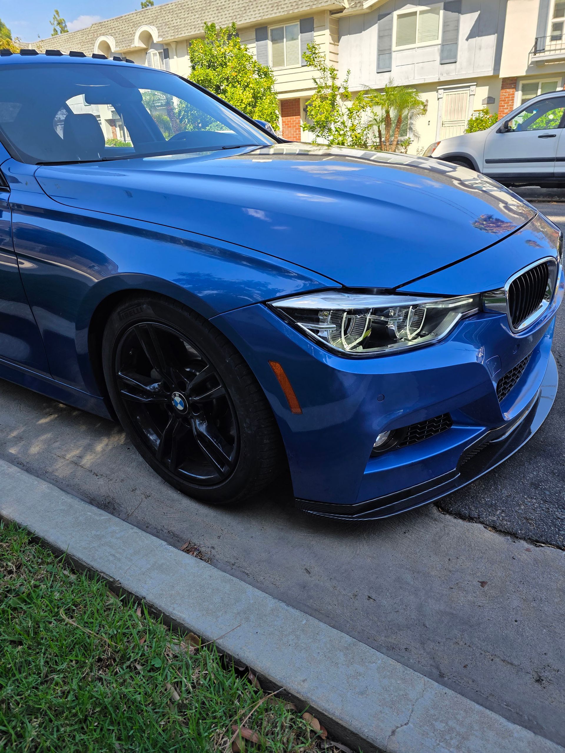 Blue sports coupe parked at the curb in a sunny suburban neighborhood
