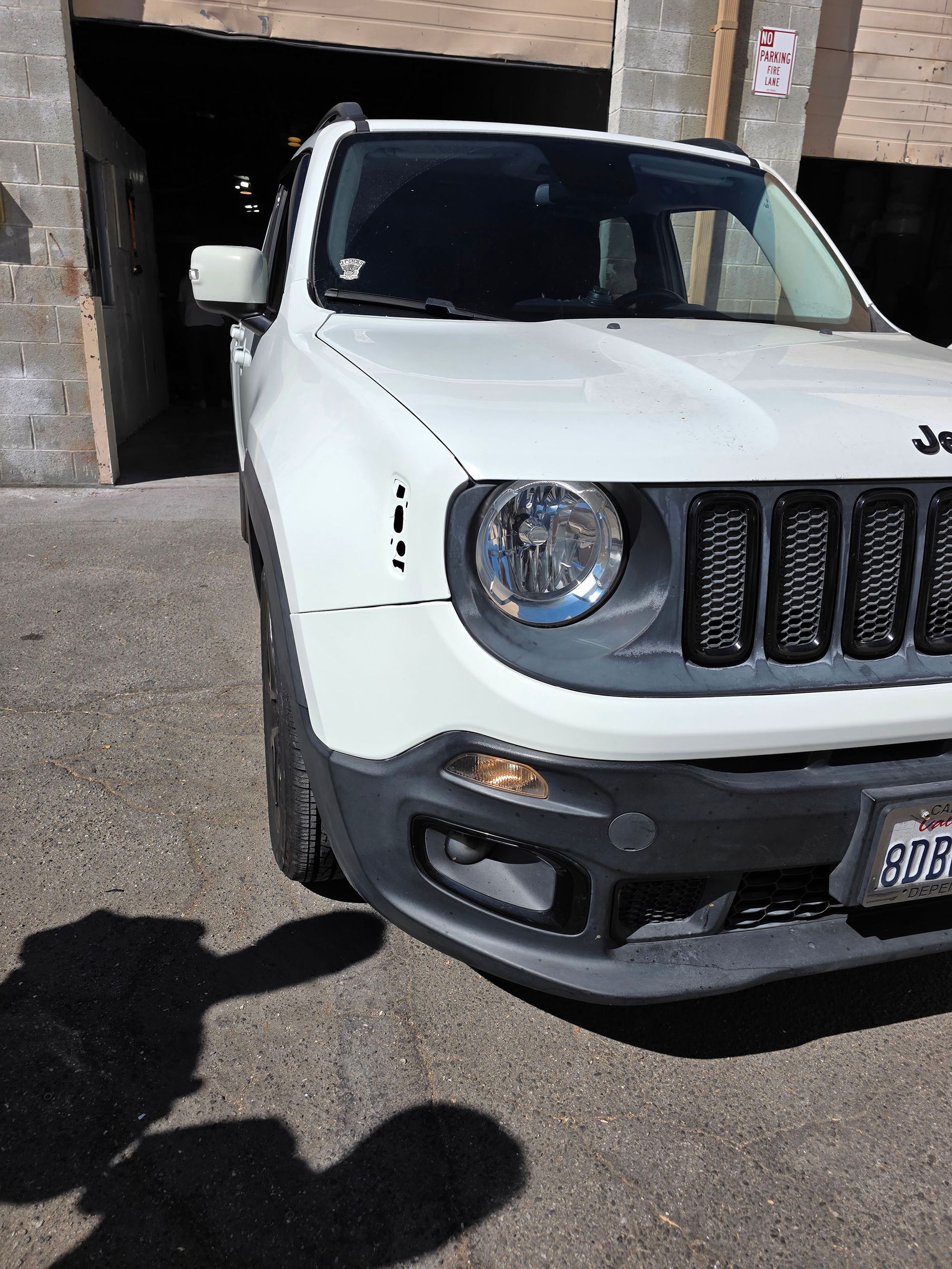 White Jeep Renegade parked outside a building, front-left view with shadow on pavement