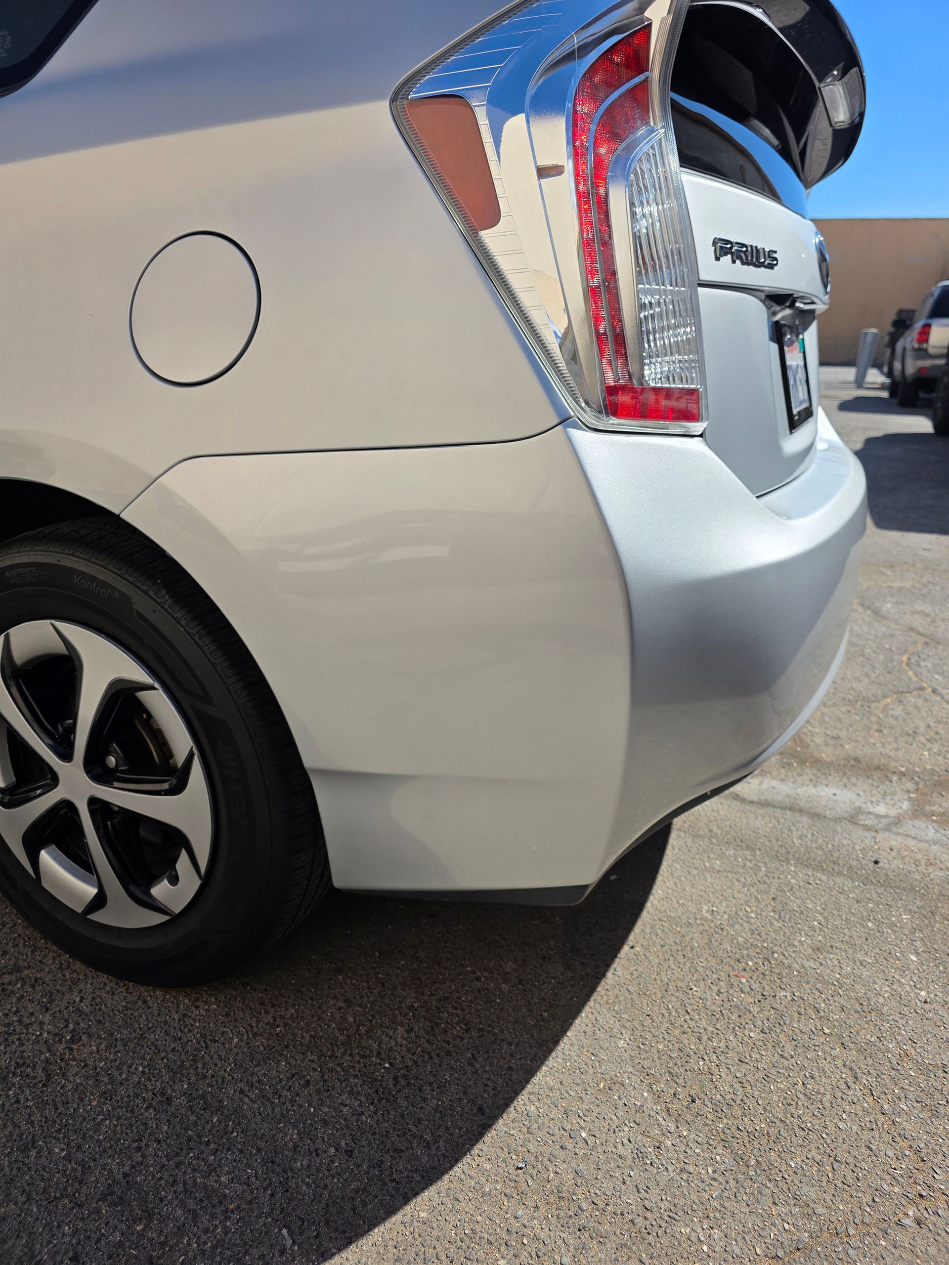 Rear side of a white SUV with a damaged taillight in a parking lot