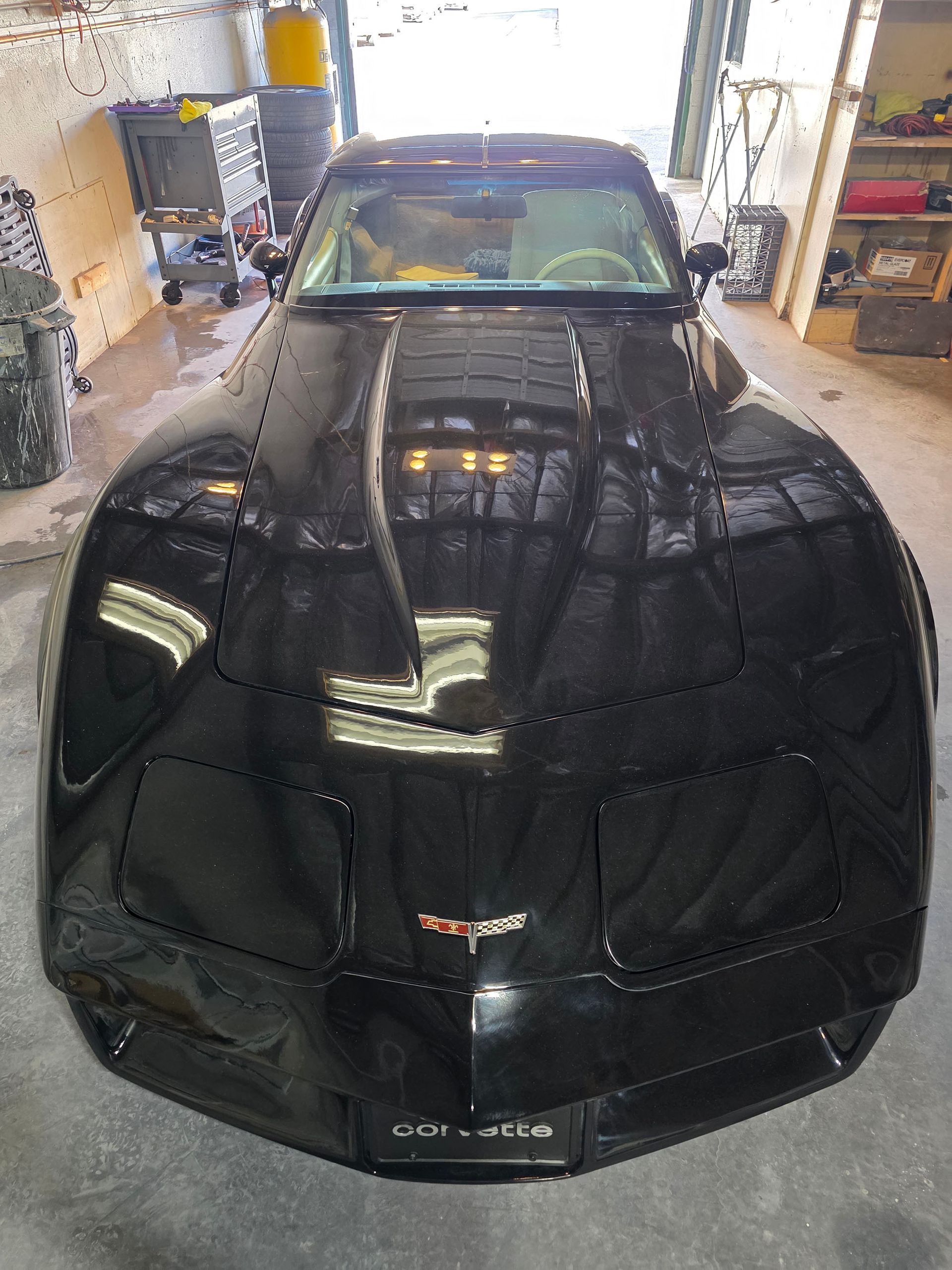 Black Chrysler sports car in a garage, front view with reflective hood and windshield.