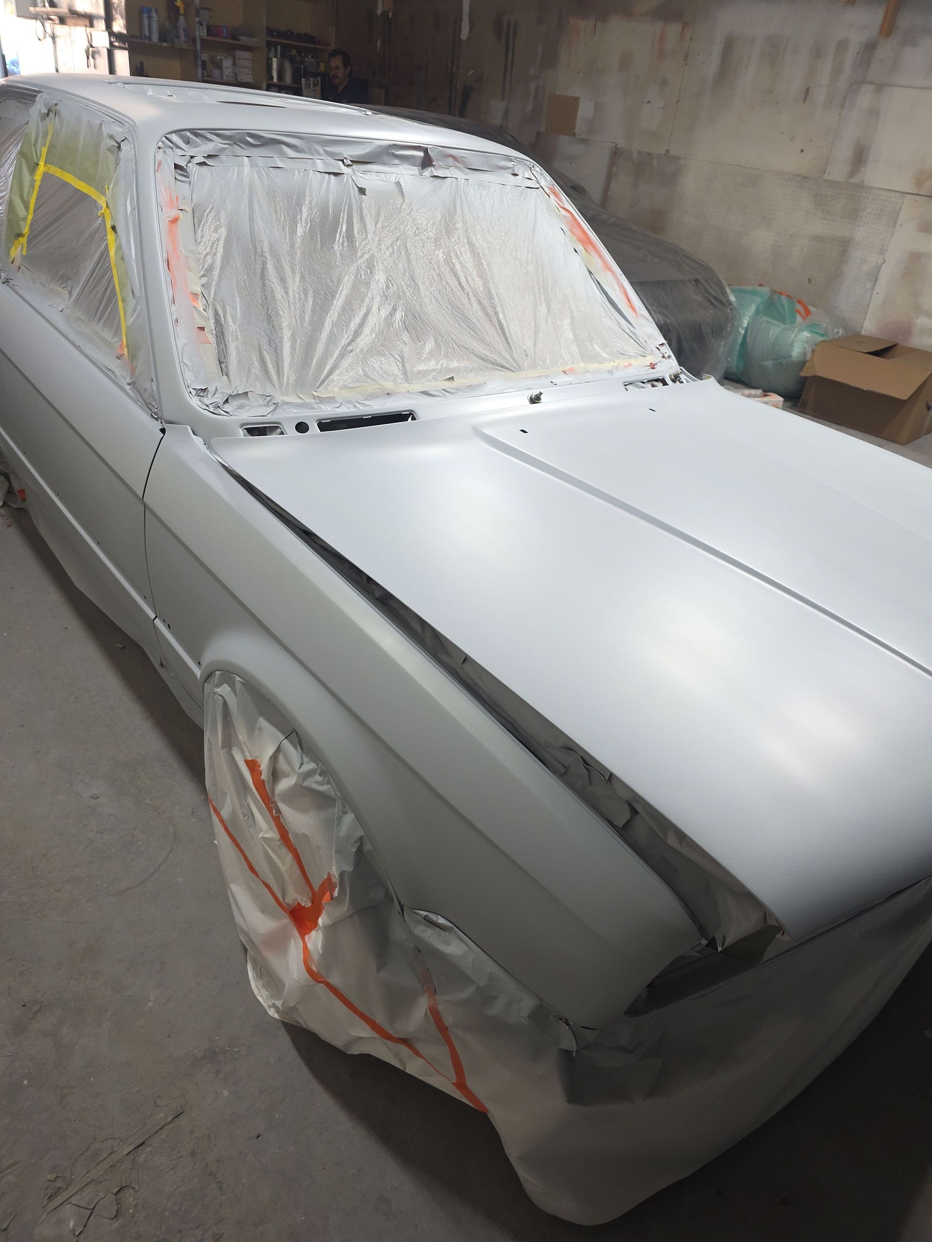 Primed sedan in a body shop, masked with plastic and ready for paint
