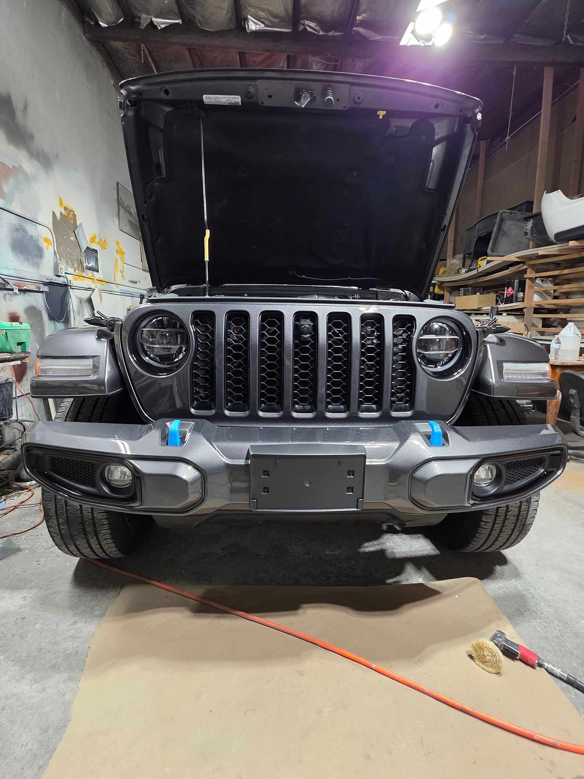 Jeep Wrangler with hood open in a garage, front view