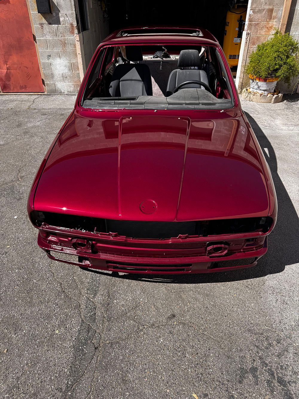 Maroon convertible sports car parked outdoors in bright sunlight