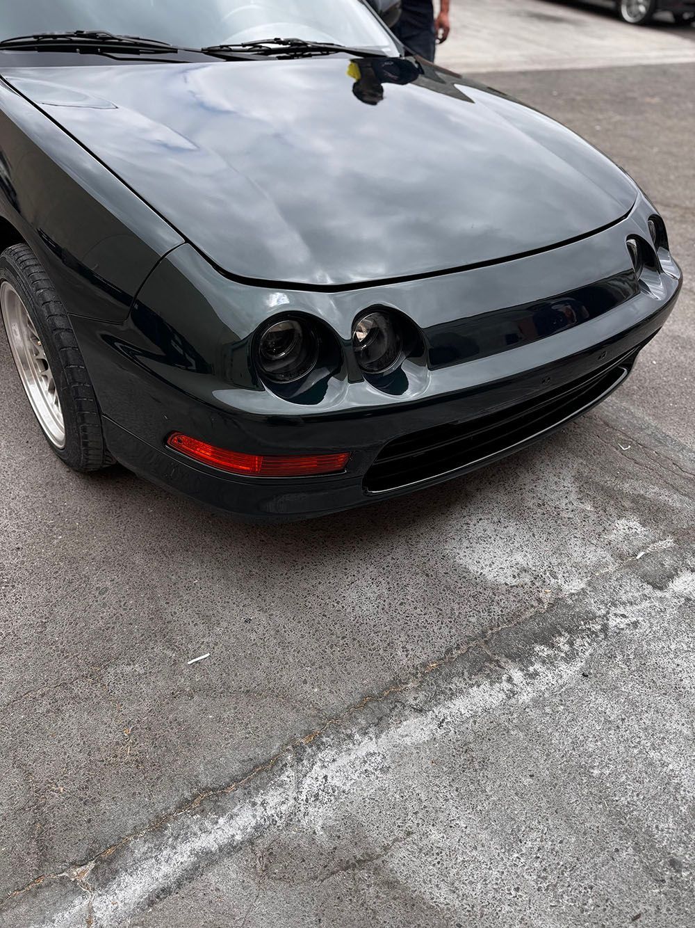 Front-left view of a black sports car with pop-up headlights on a paved lot.