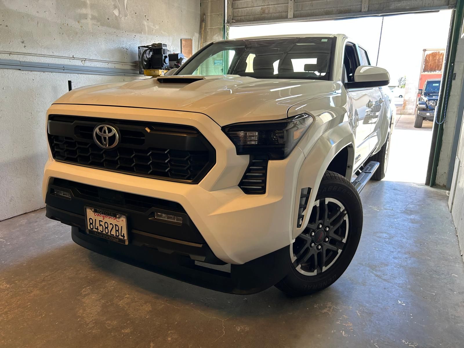 White Toyota SUV parked in a garage, front view with black grille and wheels