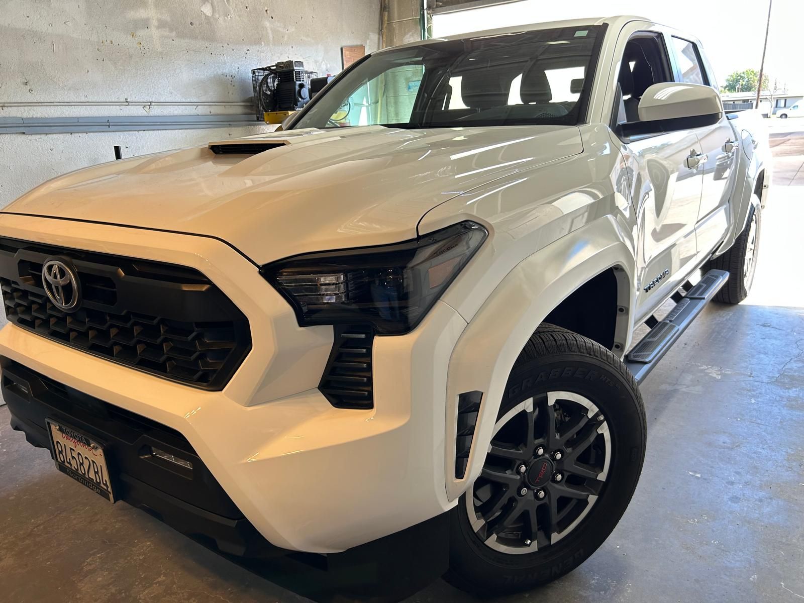 White Toyota pickup truck parked indoors in a garage, front-left view