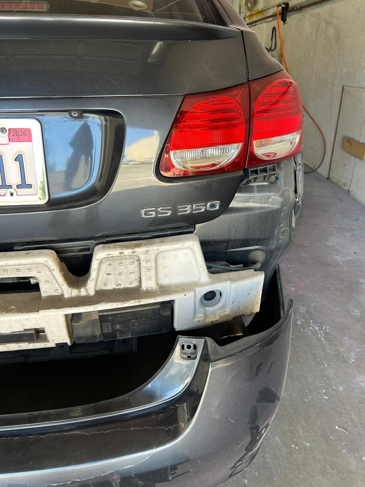 Damaged rear of a black SUV in a garage, with a dented bumper and taillights visible