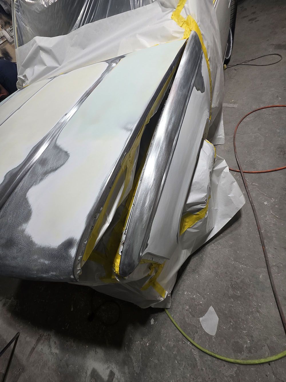Dent in silver foil-covered panel with yellow trim on a concrete floor, near a green cord