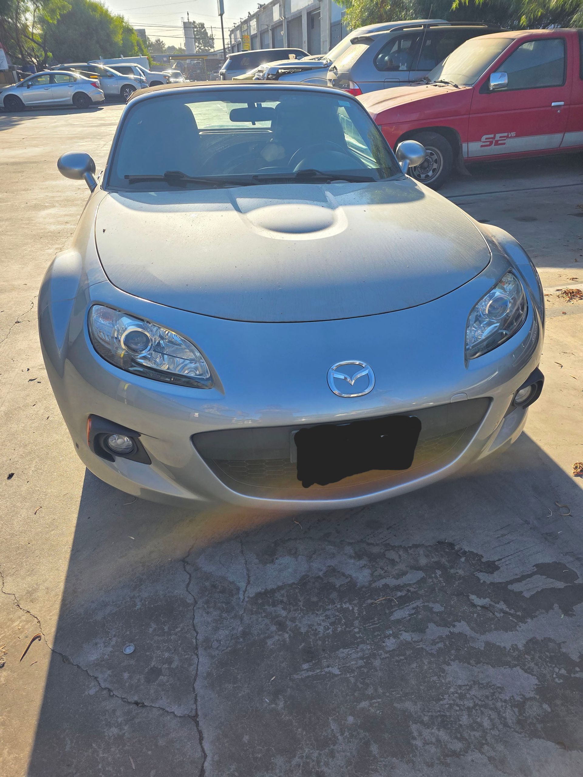 Silver Mazda convertible parked in a lot, front view in daylight