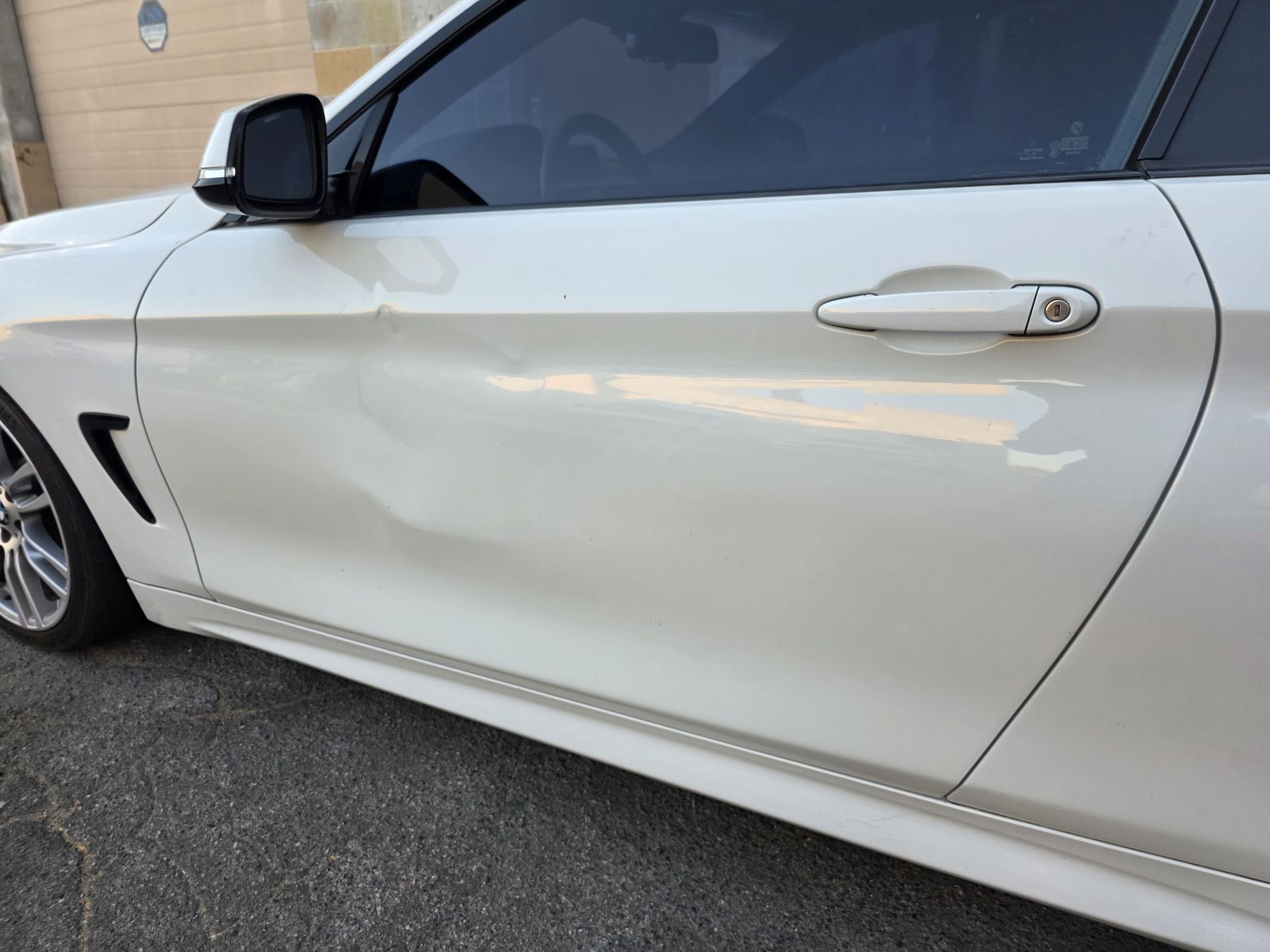 White sports car side door and mirror parked on pavement, close-up view