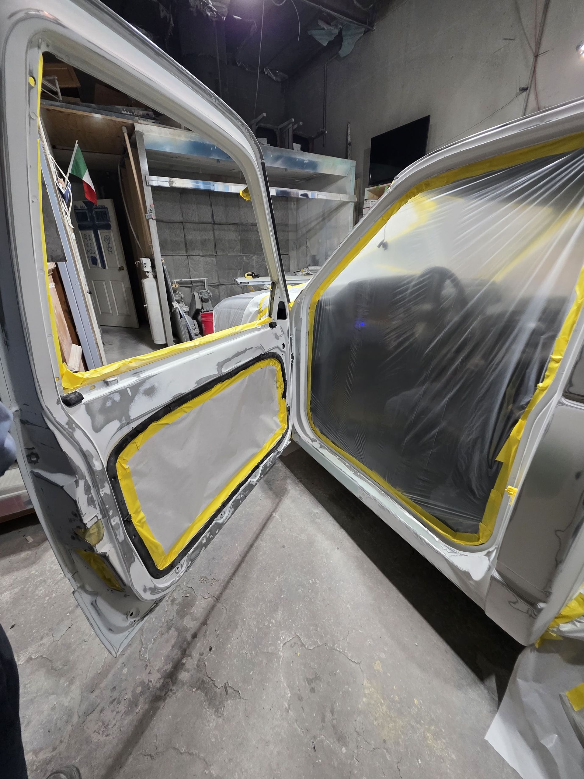 Two open van doors with taped plastic sheeting in a workshop-like garage.