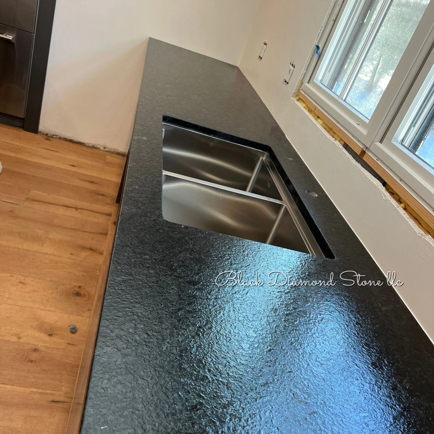 a kitchen with a black countertop and a stainless steel sink