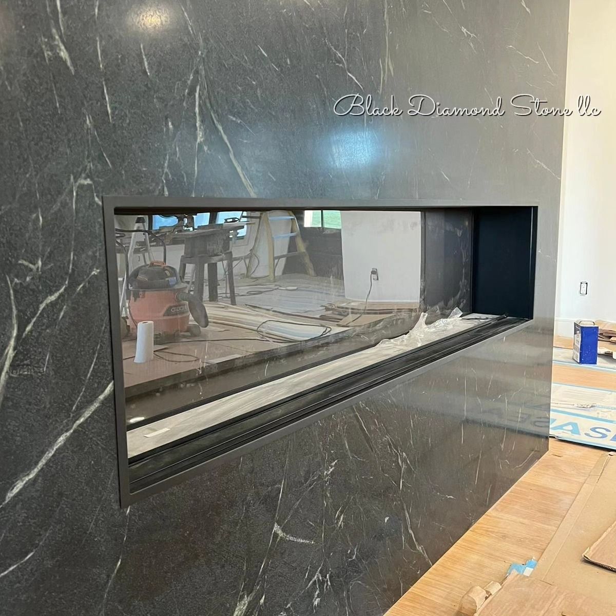 a black marble fireplace with a reflection of a kitchen in it