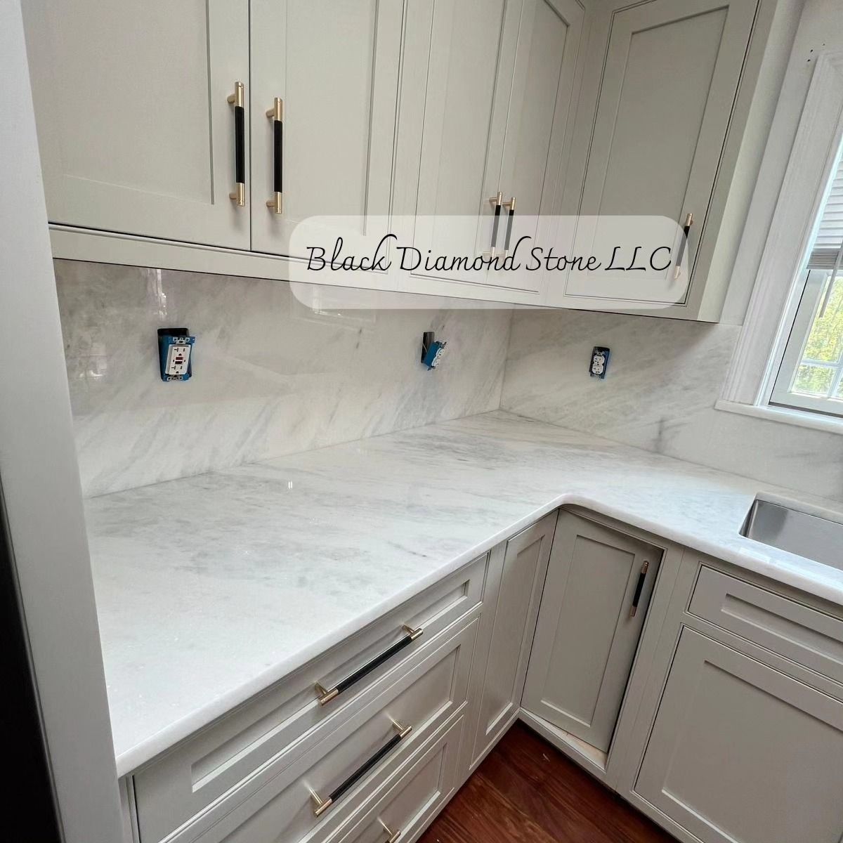 a kitchen with white cabinets and marble countertops from black diamond stone llc