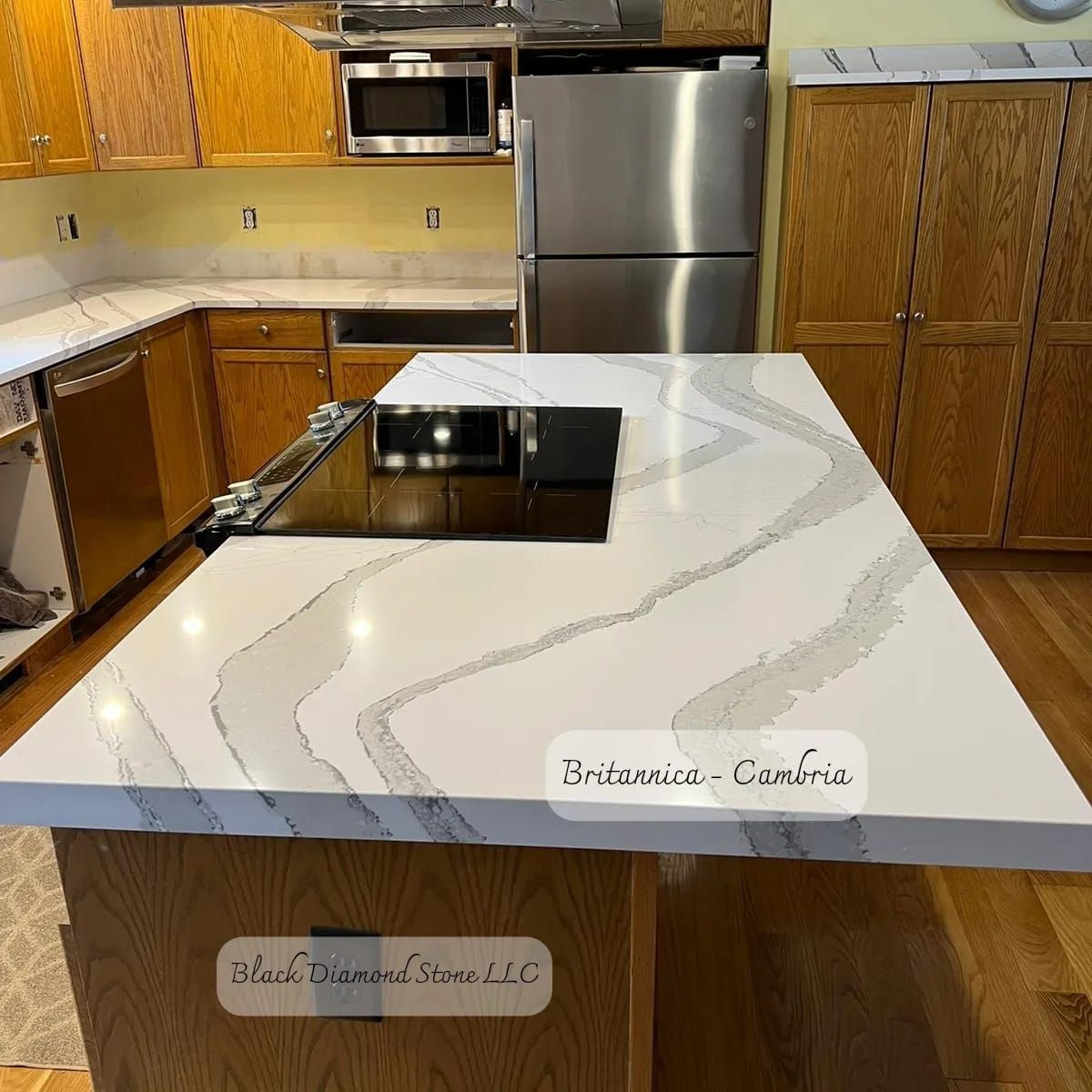 a kitchen with a white counter top and a stainless steel refrigerator