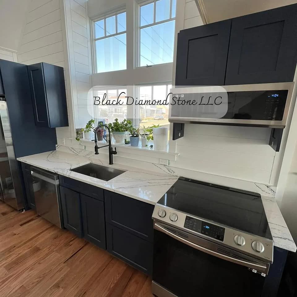 a kitchen with black cabinets, a stove, a sink, and a window
