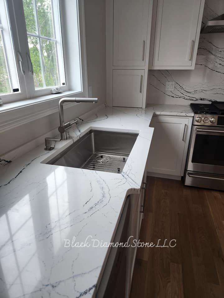 a kitchen with white cabinets, stainless steel appliances, a sink and a window