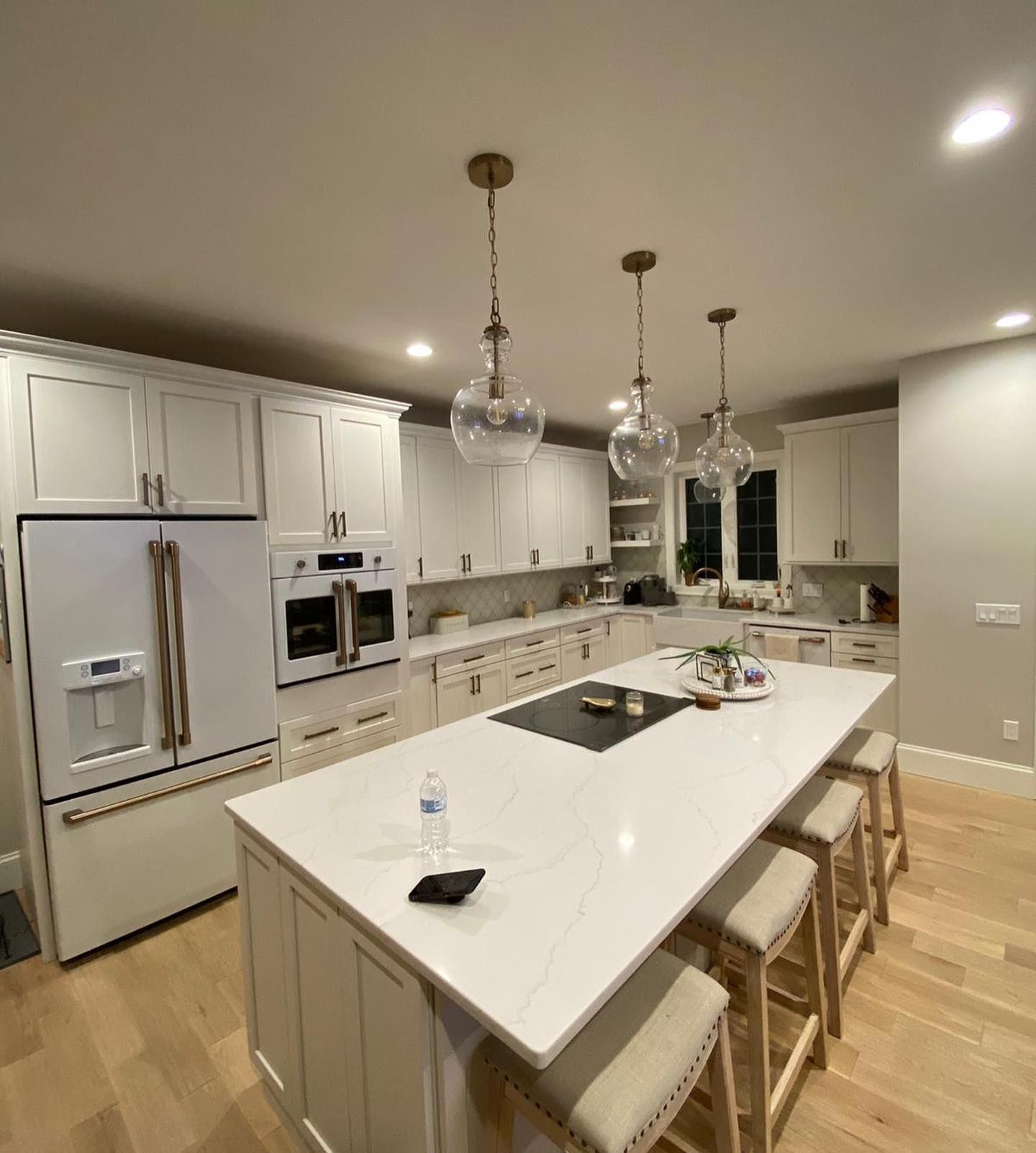 a kitchen with white cabinets and stools and a large island