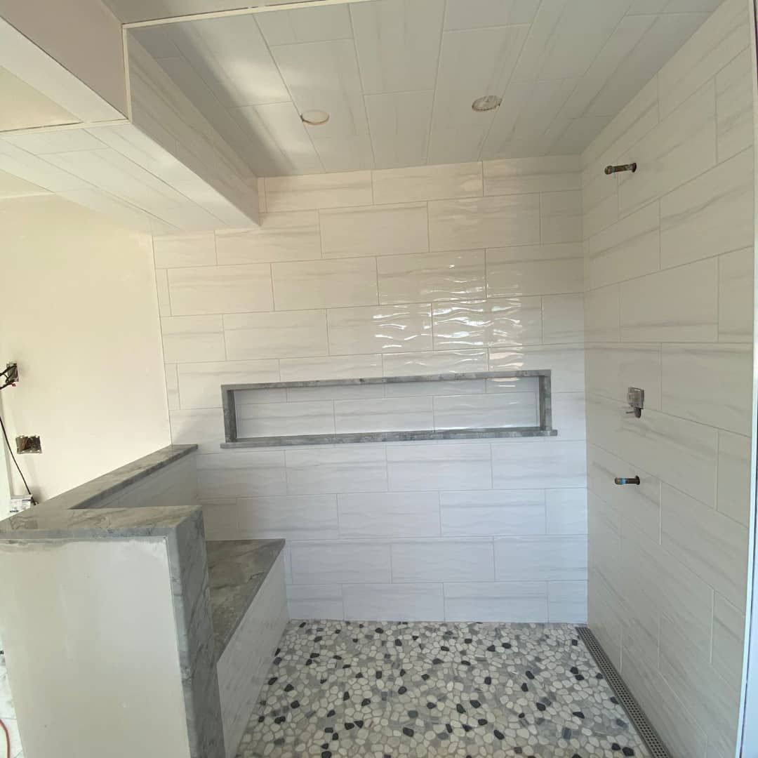 a bathroom with white tiles and a mosaic floor