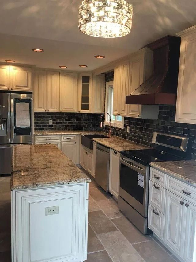 Cream kitchen with stainless steel appliances, granite countertops, and black tiled backsplash.