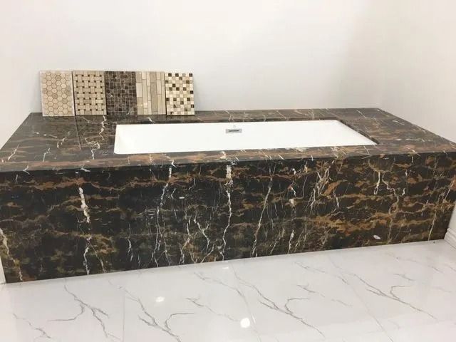 Dark marble vanity with integrated white sink and tile samples.