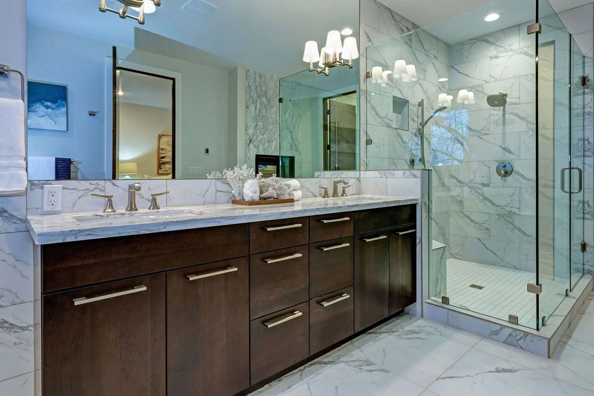 Modern bathroom with marble walls and a dark wood vanity with double sinks and a glass shower.