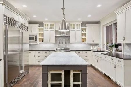 Bright, white kitchen with island, stainless steel appliances, and dark wood floor.