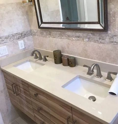Bathroom with double sinks, light countertops, wood cabinets, and large mirror.