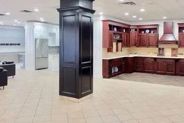 Interior showroom displaying kitchen and cabinetry with dark wood column in the foreground.