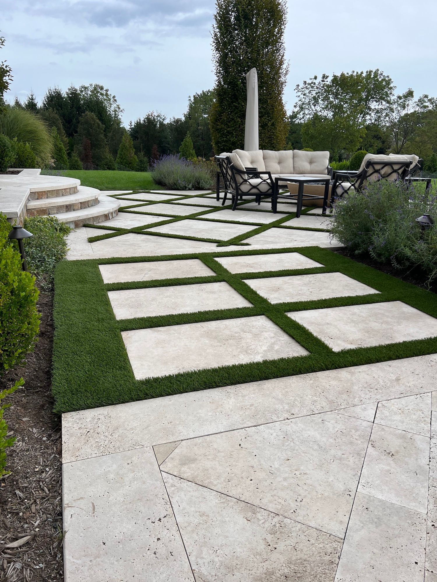 A patio with a couch , chairs , table and umbrella.