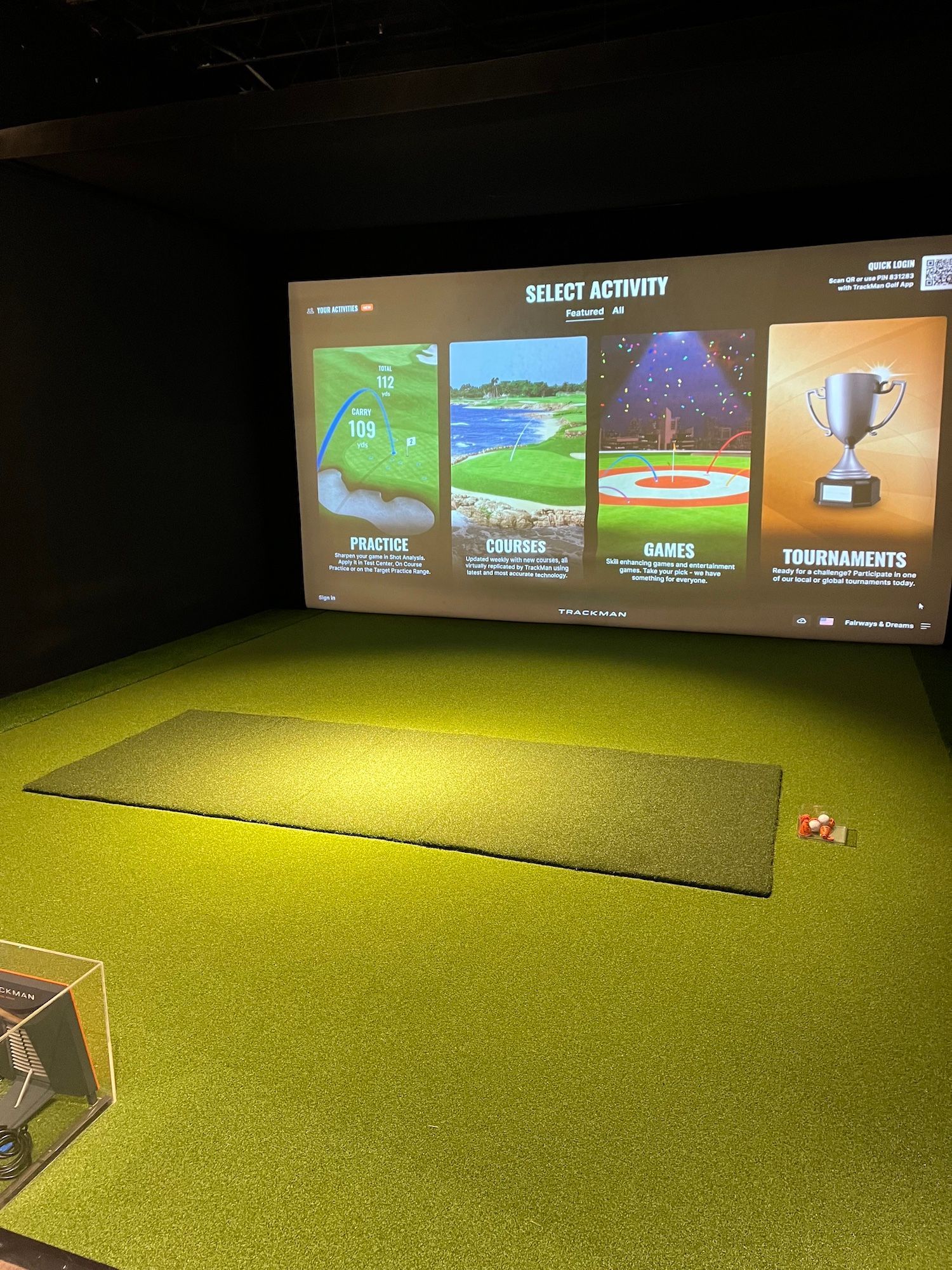 A golf simulator with a large screen on the wall.