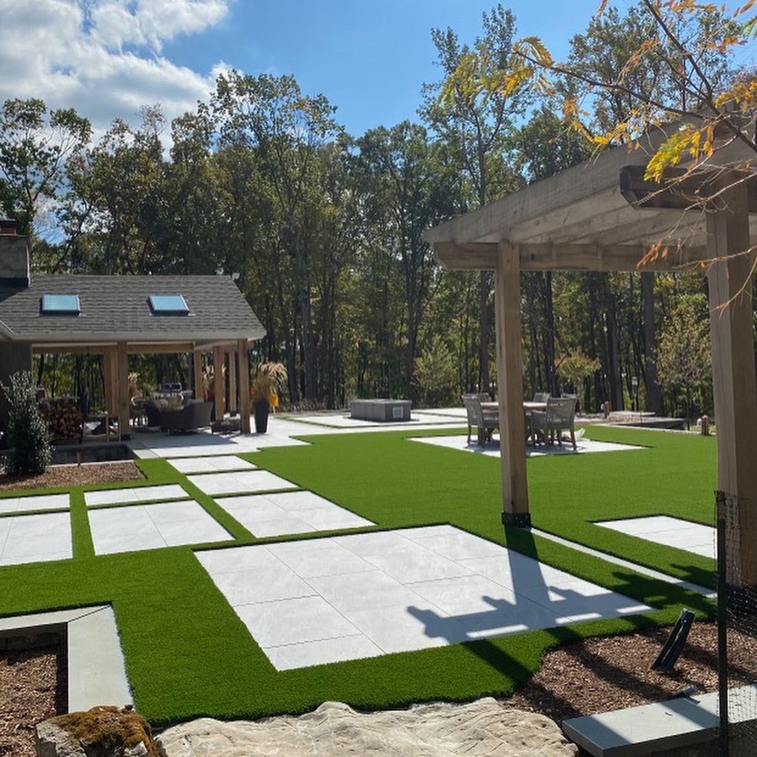 A large lawn with a pergola and a house in the background.
