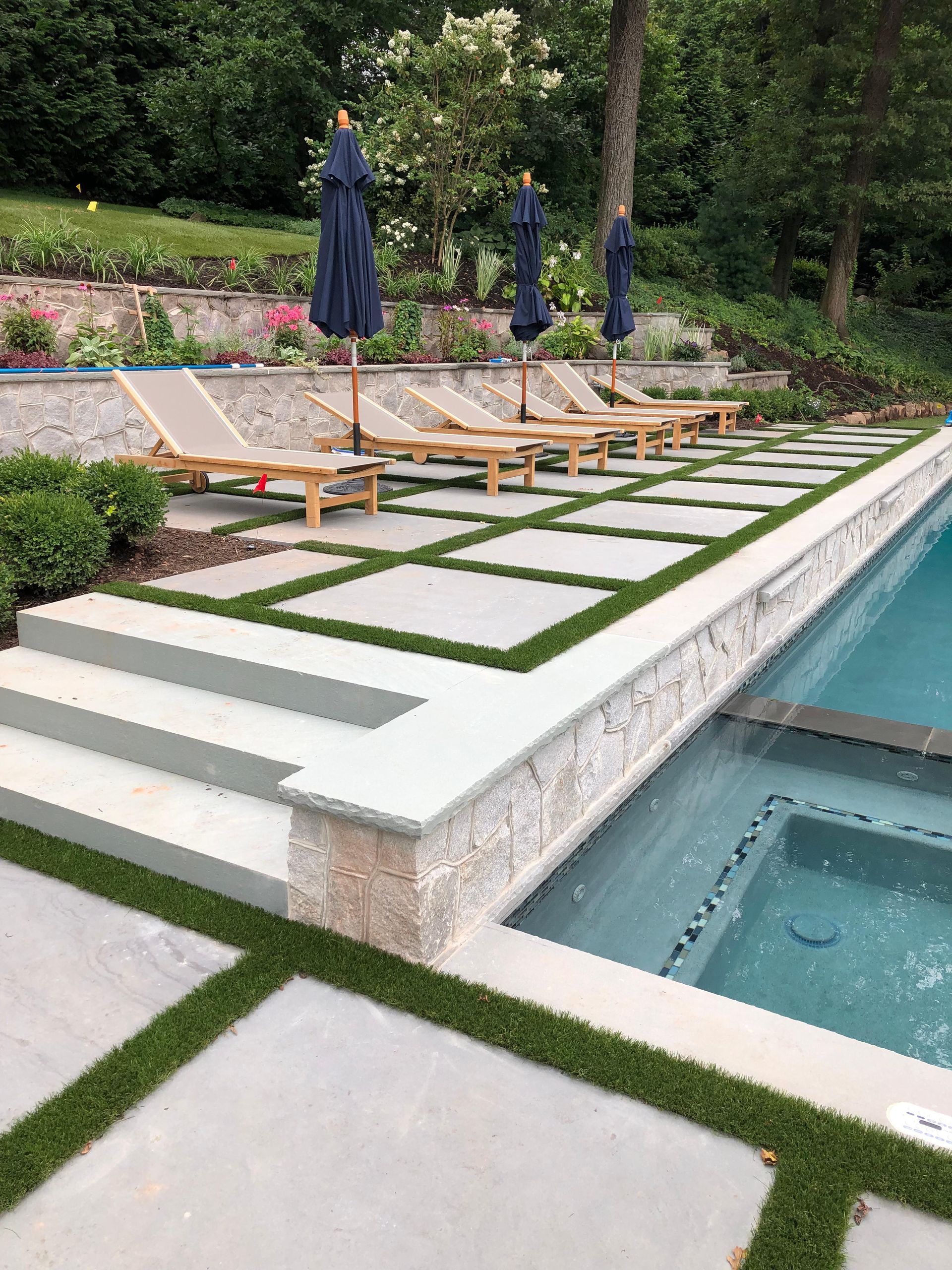 A large swimming pool surrounded by lawn chairs and umbrellas.