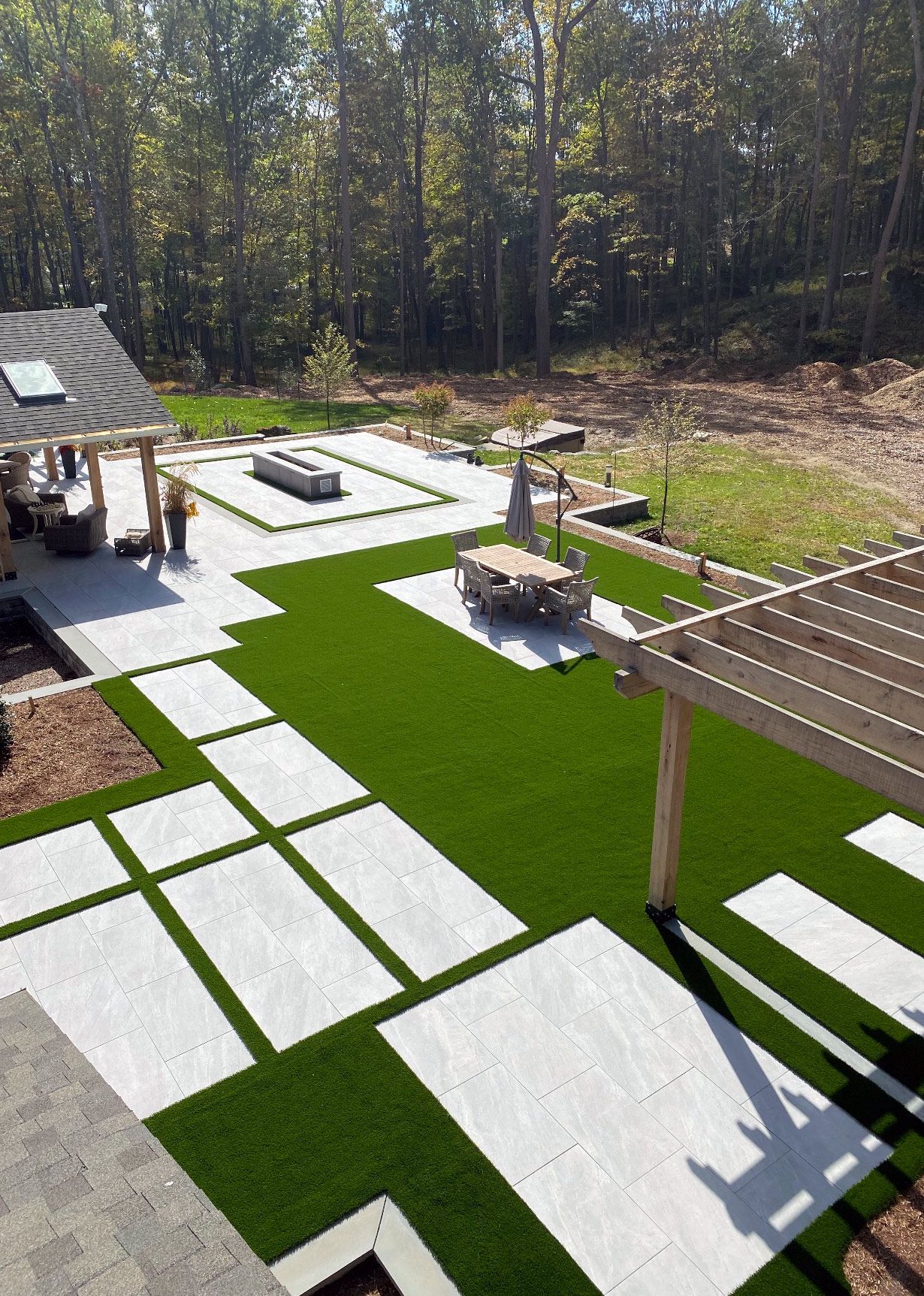 An aerial view of a lush green lawn with white tiles and a pergola.