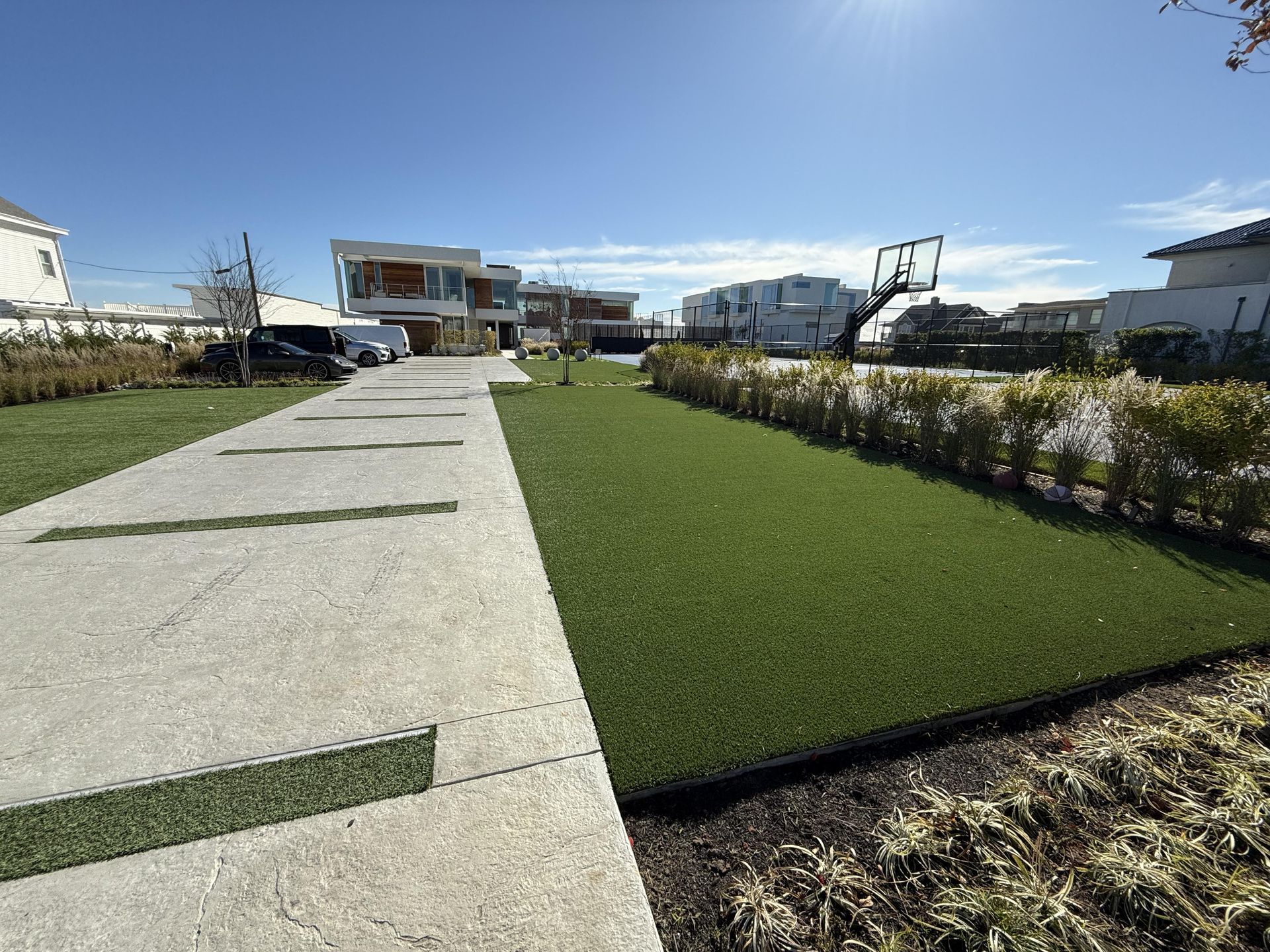 A walkway leading to a house with a basketball hoop in the background.