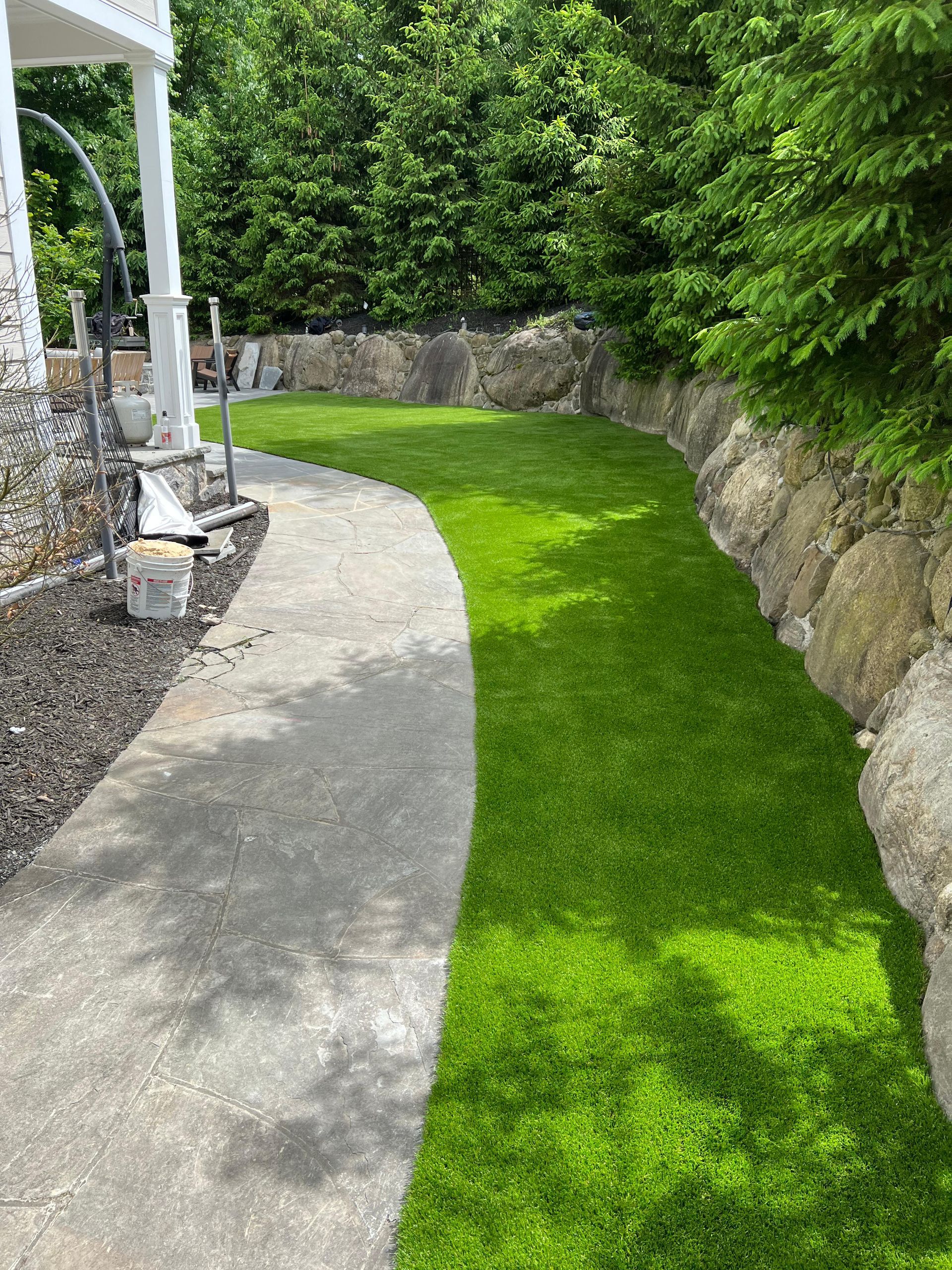A concrete walkway leading to a lush green lawn.