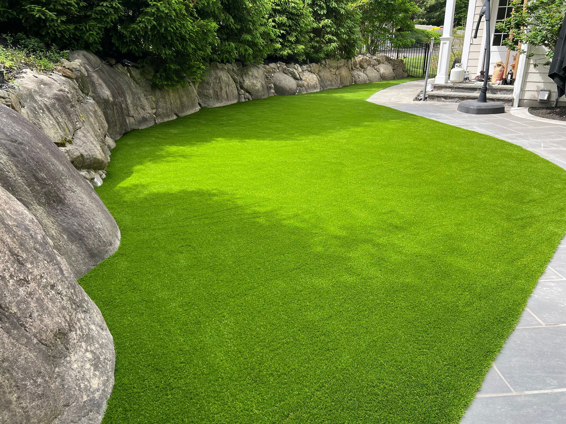 A lush green lawn surrounded by rocks and a stone walkway.