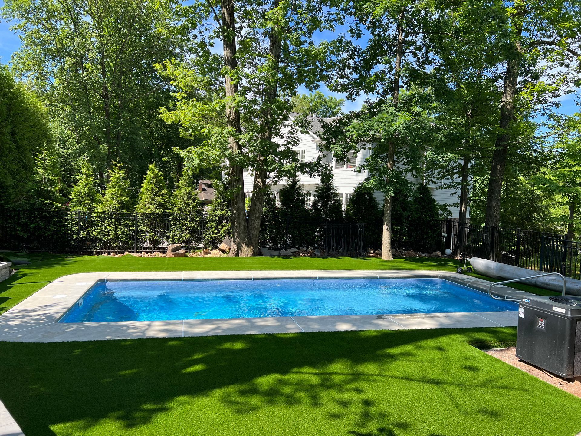 A large swimming pool surrounded by trees in a backyard.